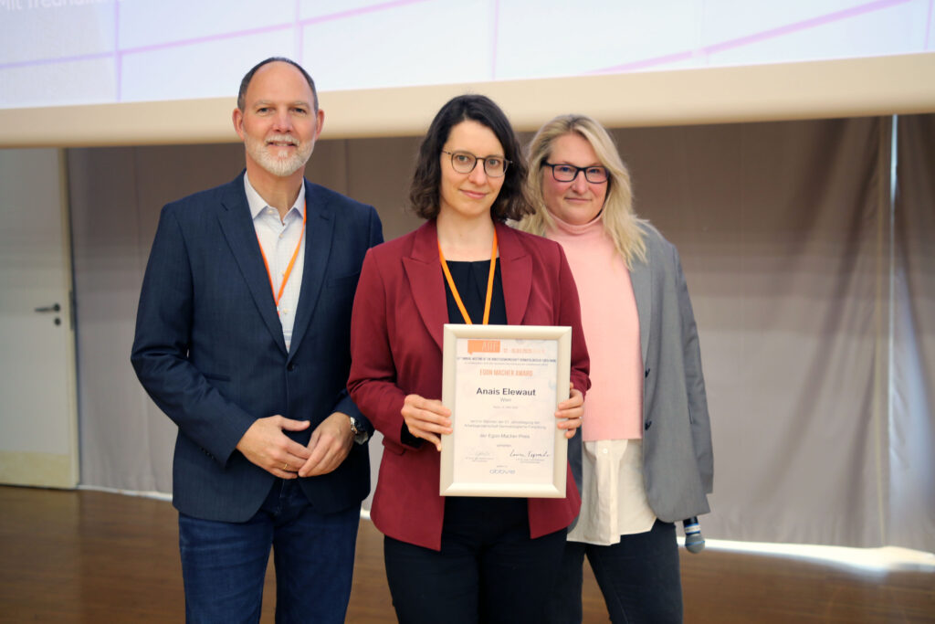 Presentation of the Egon Macher Prize to Enais Elewaut in absentia; center: L. Erpenbeck (ADF Board Member), left: S. Oelmann (representative of the sponsor AbbVie Deutschland GmbH & Co. KG), right: K. Loser (Chair of the Prize Board of Trustees)